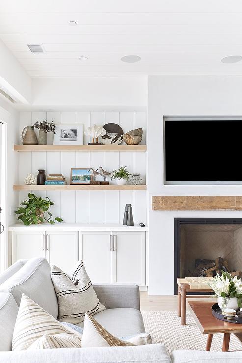 shiplap ceiling shiplap wall details wood open shelves storage fireplace with wood mantle tv over mantle large grey sectional with throw pillows wooden coffee table bench wool jute area rug