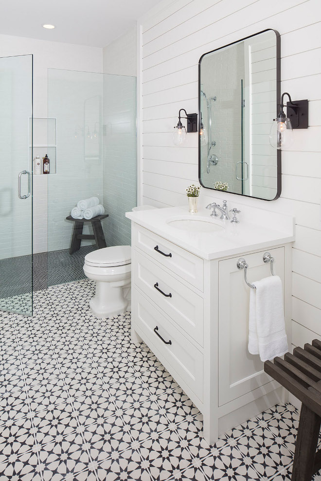 bathroom white vanity shiplap walls black mirror with sconces chrome hardware walk in shower star patterned tile floor black shower tile white subway tile wood bench with towels
